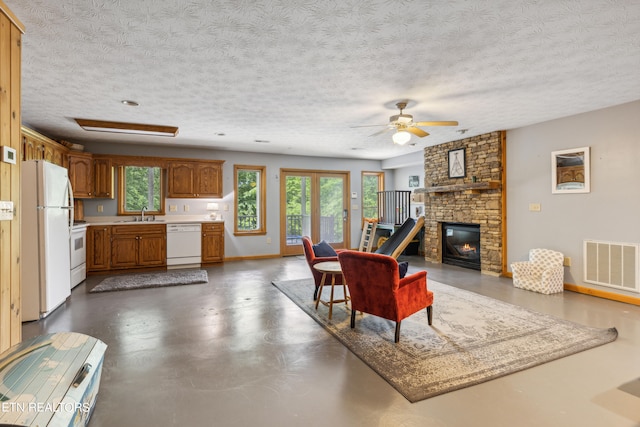 living room featuring a textured ceiling, plenty of natural light, a large fireplace, and ceiling fan