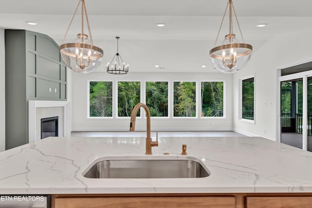 kitchen with dishwasher, decorative light fixtures, light stone countertops, a chandelier, and sink