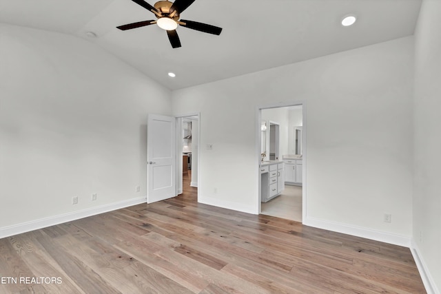 unfurnished bedroom featuring lofted ceiling, ensuite bath, light wood-type flooring, and ceiling fan