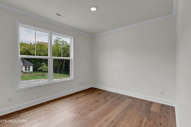 empty room with ornamental molding, hardwood / wood-style flooring, and plenty of natural light