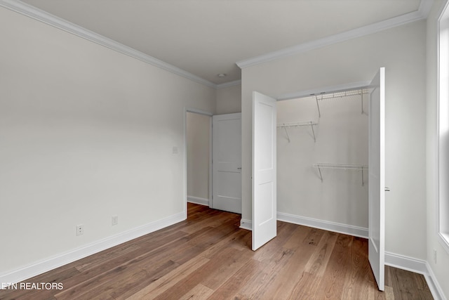 unfurnished bedroom with crown molding, hardwood / wood-style floors, and a closet