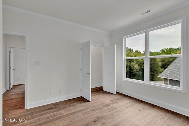 unfurnished bedroom with ornamental molding and light wood-type flooring