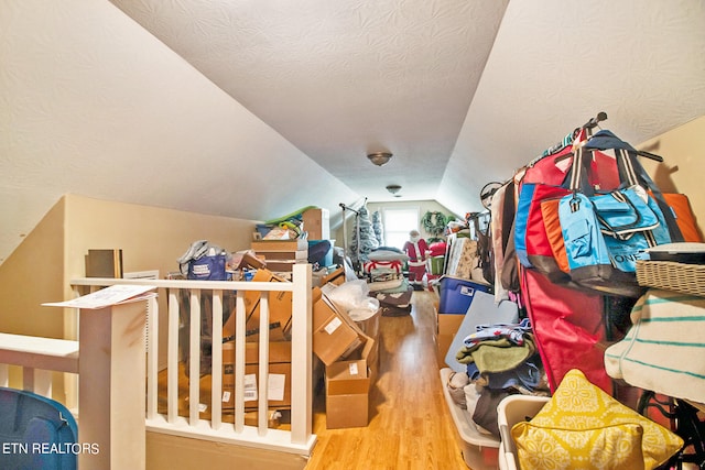 interior space with hardwood / wood-style flooring, a textured ceiling, and lofted ceiling