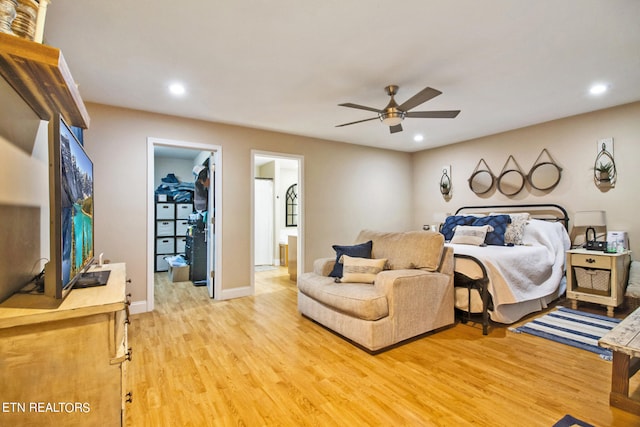 bedroom with a closet, ceiling fan, ensuite bath, a walk in closet, and wood-type flooring