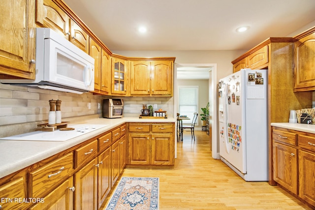 kitchen with white appliances, tasteful backsplash, and light hardwood / wood-style flooring