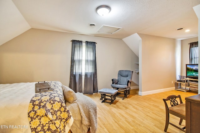 bedroom featuring lofted ceiling, hardwood / wood-style flooring, and a textured ceiling