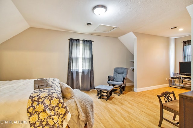 bedroom featuring hardwood / wood-style flooring, a textured ceiling, and vaulted ceiling