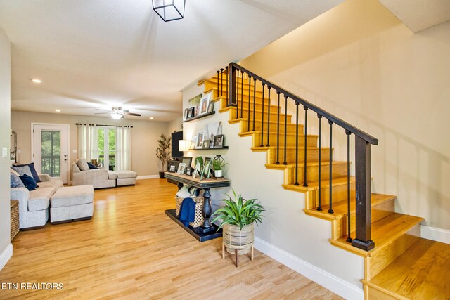 stairs featuring ceiling fan and hardwood / wood-style flooring