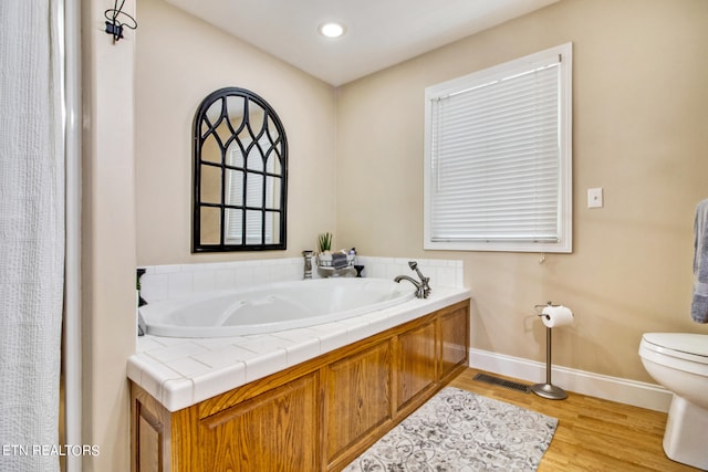 bathroom with a washtub, wood-type flooring, and toilet