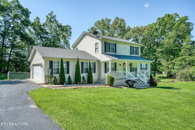 view of front of house featuring a garage, a front yard, and covered porch