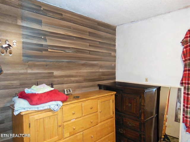 interior space with a textured ceiling and wood walls