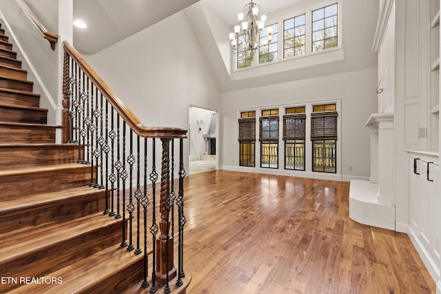 foyer entrance featuring high vaulted ceiling, plenty of natural light, a notable chandelier, and light hardwood / wood-style floors