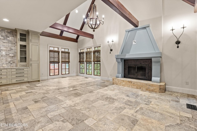 unfurnished living room featuring a fireplace, beam ceiling, an inviting chandelier, and high vaulted ceiling