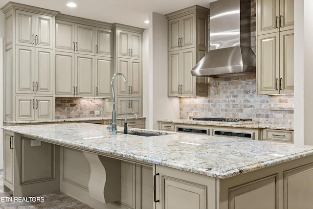 kitchen featuring light stone countertops, wall chimney range hood, gas stovetop, and decorative backsplash