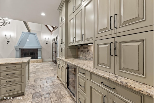 kitchen with wine cooler, backsplash, light stone counters, and a fireplace