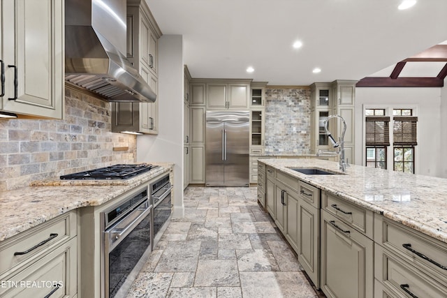 kitchen featuring wall chimney exhaust hood, sink, backsplash, and appliances with stainless steel finishes