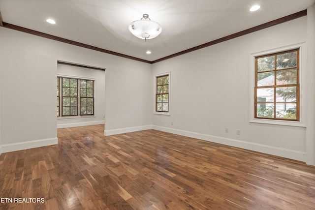 empty room with wood-type flooring, plenty of natural light, and crown molding