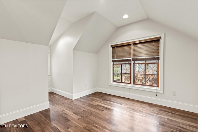 additional living space with hardwood / wood-style flooring and vaulted ceiling