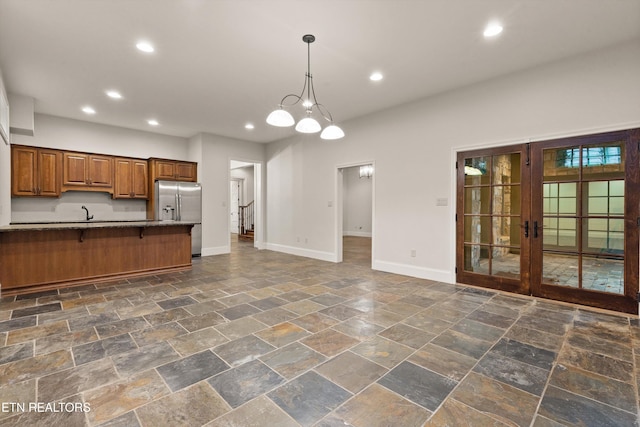 kitchen featuring stainless steel refrigerator with ice dispenser, a breakfast bar area, an inviting chandelier, pendant lighting, and french doors