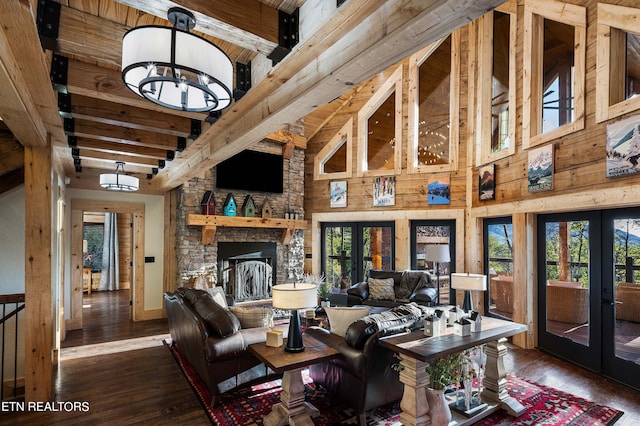 living room featuring an inviting chandelier, wooden walls, dark hardwood / wood-style floors, a towering ceiling, and french doors