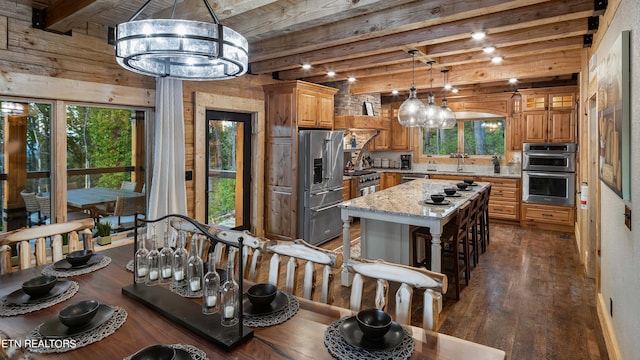 kitchen featuring light stone countertops, a center island, high end appliances, a chandelier, and beam ceiling