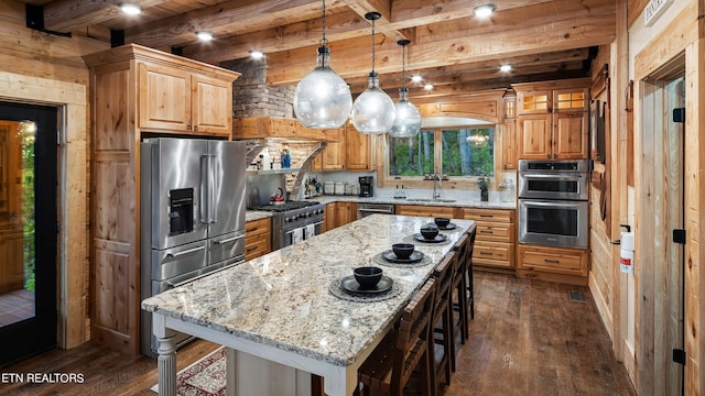 kitchen with a center island, beamed ceiling, hanging light fixtures, light stone countertops, and high quality appliances