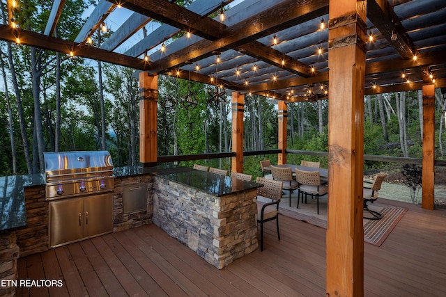 deck featuring grilling area, a pergola, an outdoor kitchen, and exterior bar