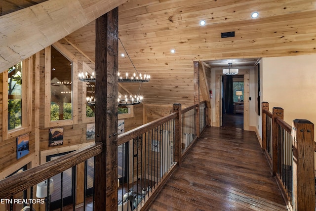 hall with lofted ceiling, wood ceiling, dark wood-type flooring, wood walls, and a notable chandelier