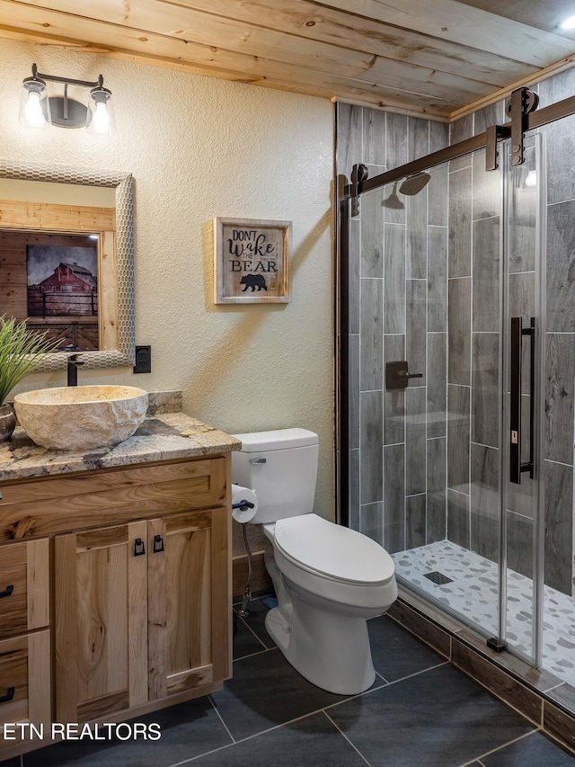 bathroom featuring tile patterned flooring, vanity, toilet, a shower with shower door, and wooden ceiling