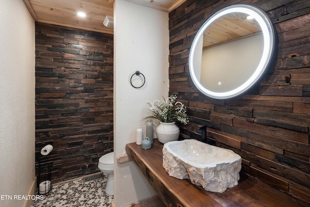 bathroom with toilet, wooden ceiling, and sink