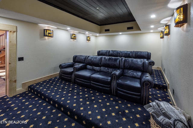 carpeted cinema room with wood ceiling and a tray ceiling