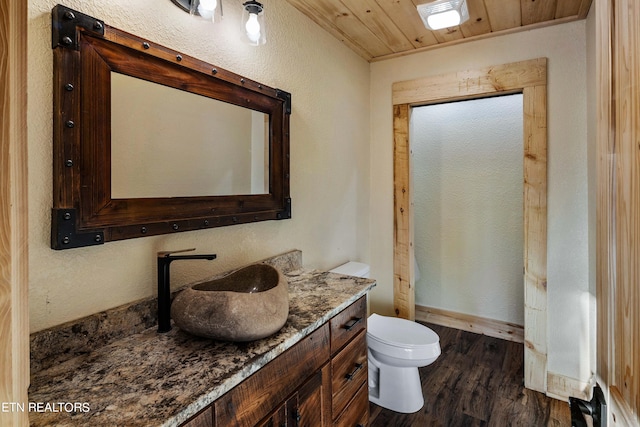 bathroom with hardwood / wood-style flooring, wooden ceiling, toilet, and vanity