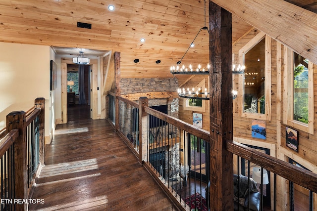 corridor featuring wooden walls, dark wood-type flooring, wood ceiling, high vaulted ceiling, and a chandelier