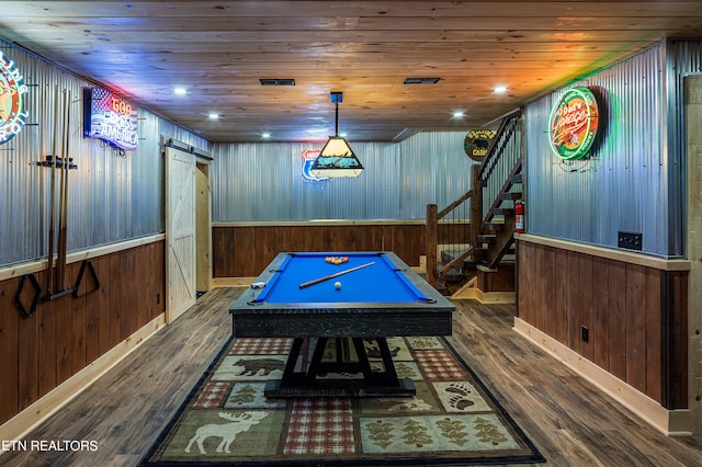 recreation room with a barn door, dark wood-type flooring, wooden walls, and wooden ceiling
