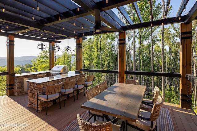 wooden terrace featuring area for grilling, an outdoor wet bar, a mountain view, grilling area, and a pergola