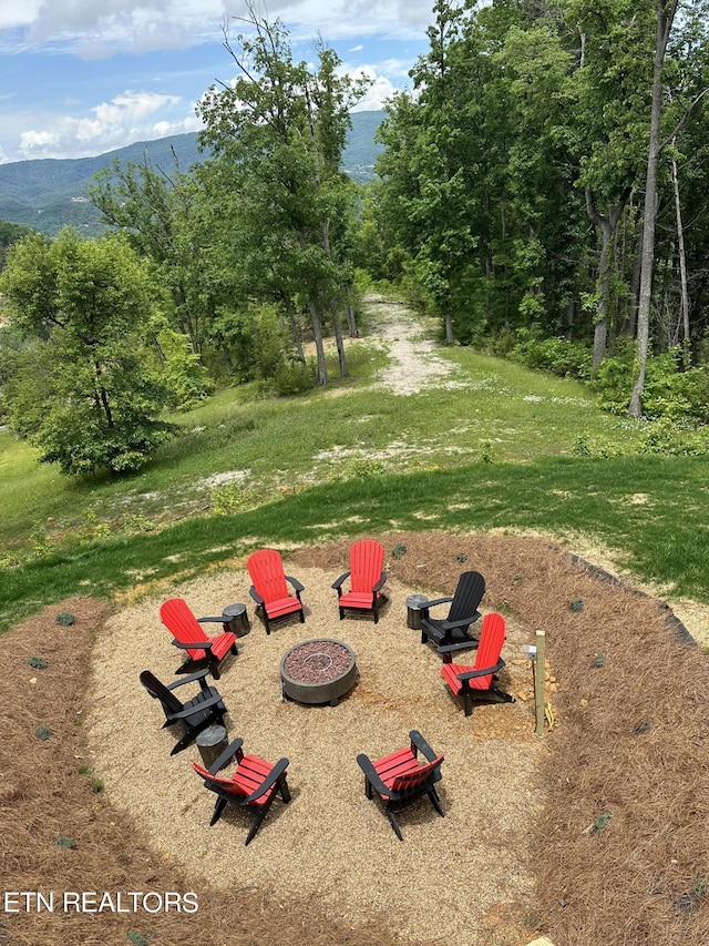 surrounding community with a mountain view, an outdoor fire pit, and a yard