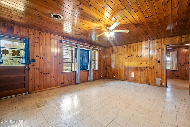 empty room with wooden walls, light tile floors, and wooden ceiling