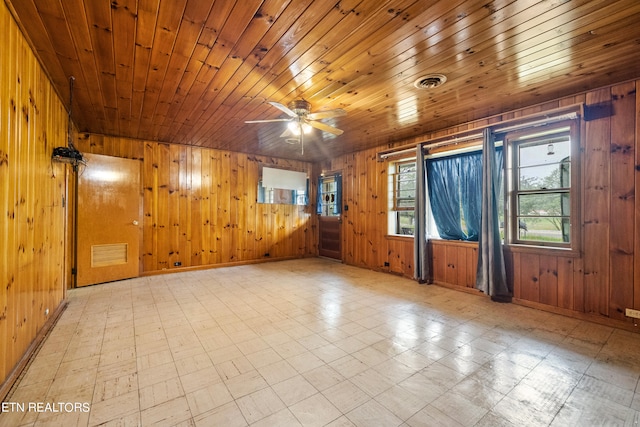 tiled empty room featuring wood ceiling, wood walls, and ceiling fan