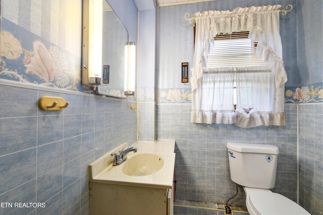 bathroom with tile walls, vanity, and toilet