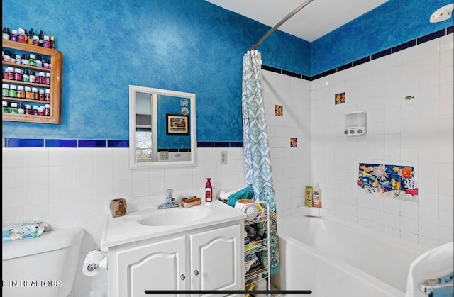 full bathroom with tile walls, shower / tub combo with curtain, vanity, and toilet