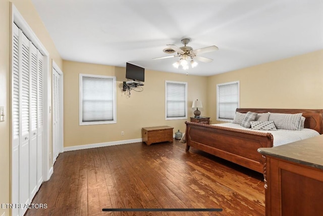 bedroom featuring dark wood-type flooring, multiple closets, ceiling fan, and multiple windows