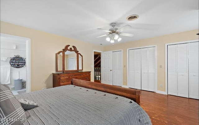 bedroom with wood-type flooring, ceiling fan, and multiple closets