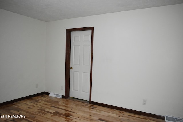 empty room featuring a textured ceiling and hardwood / wood-style flooring