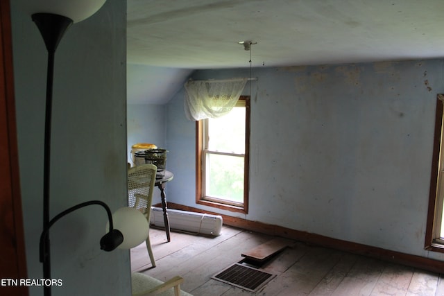 interior space with lofted ceiling, light hardwood / wood-style floors, and a baseboard radiator