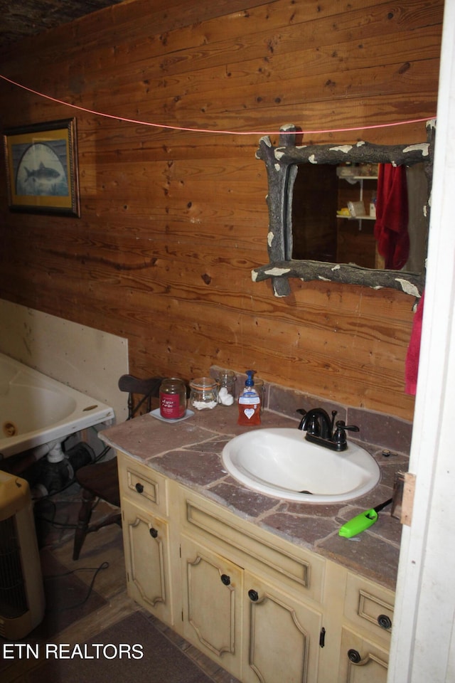 bathroom featuring vanity, a tub, and wooden walls