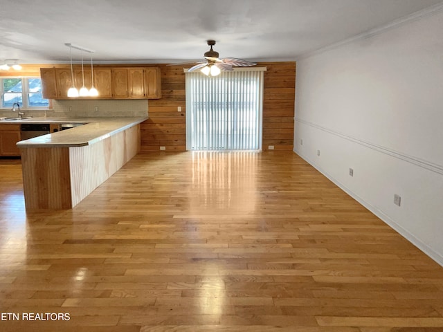 kitchen with ceiling fan, light hardwood / wood-style floors, crown molding, kitchen peninsula, and sink