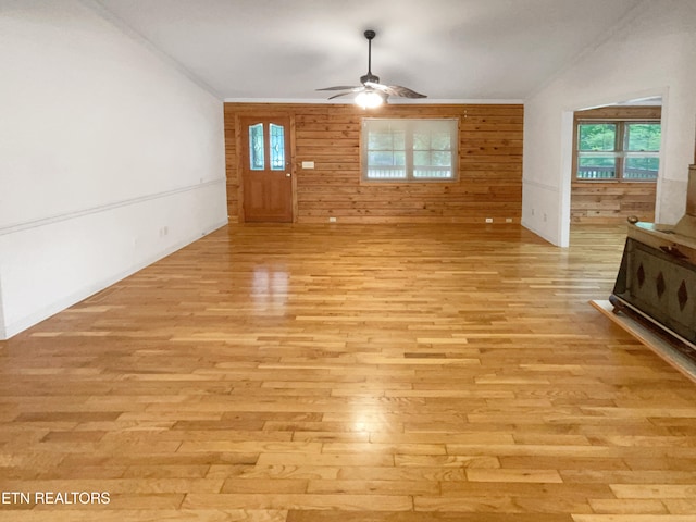 unfurnished living room with ceiling fan, wooden walls, and light hardwood / wood-style flooring