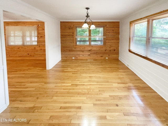 empty room featuring plenty of natural light, light wood-type flooring, and a notable chandelier