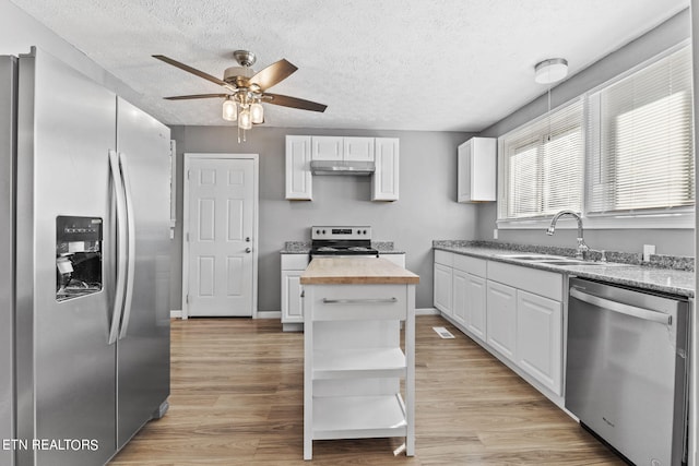 kitchen with ceiling fan, light wood-type flooring, a kitchen island, white cabinetry, and appliances with stainless steel finishes