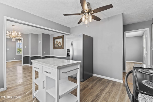 kitchen with white cabinetry, a textured ceiling, ceiling fan with notable chandelier, wood-type flooring, and stainless steel refrigerator with ice dispenser